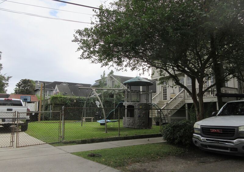 A residential backyard with a wooden playset visible behind a chain-link fence