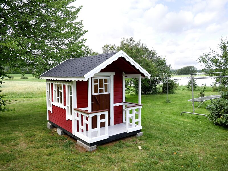 Red and white wooden backyard playhouse on green grass